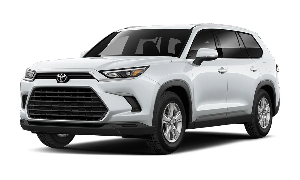 2025 Toyota Highlander Hybrid SUV white in color pictured from a front three-quarter view, showcasing its distinctive chrome-accented grille, sleek LED headlights, aerodynamic body shape, and spacious, family-friendly design with hybrid efficiency.